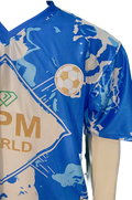 Close-up of OPM World gold logo and green diamond crest on professional-grade football kit.