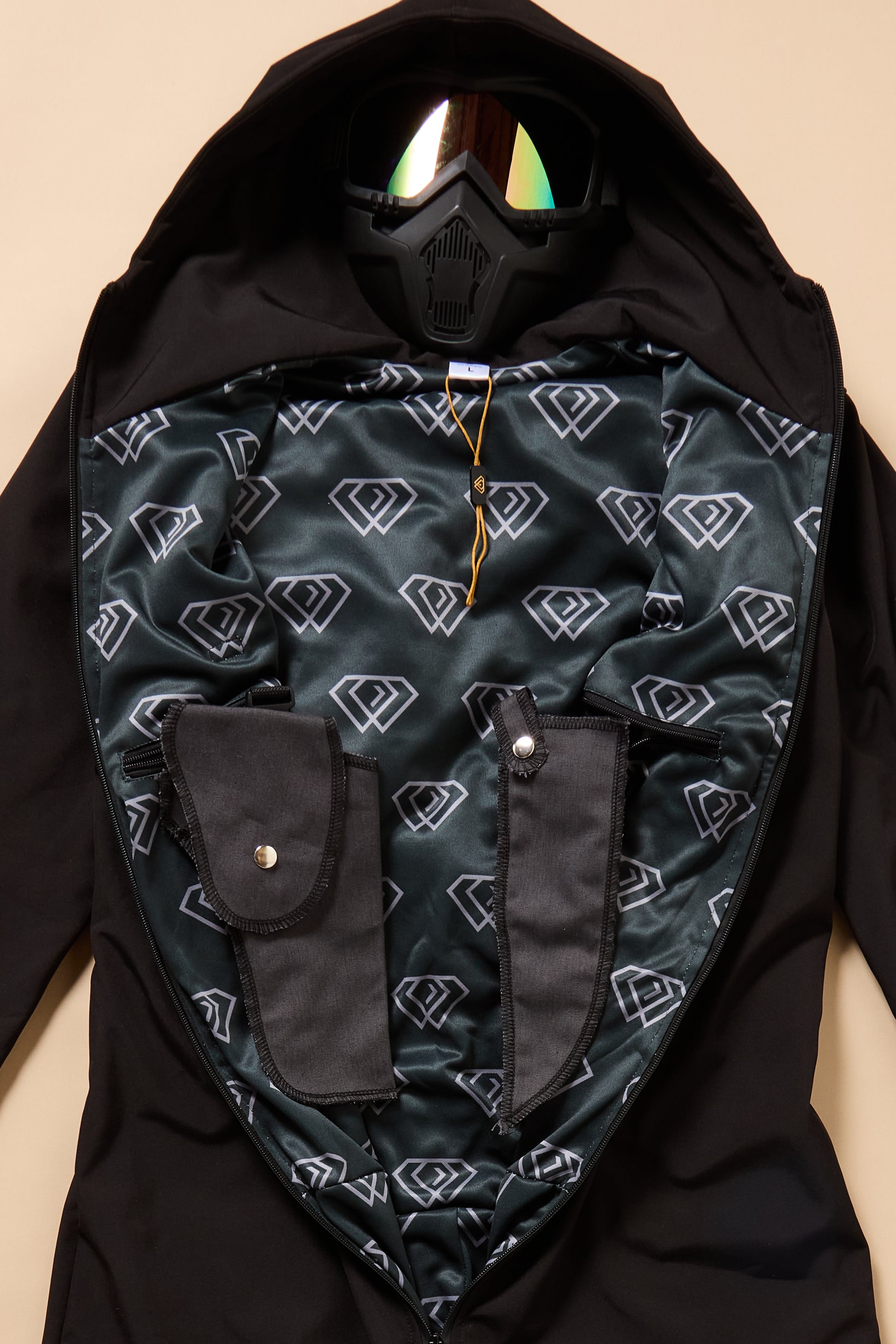 Black jacket with patterned lining and reflective goggles on a beige background