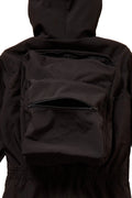 Black backpack worn by a person in a black jacket on a white background
