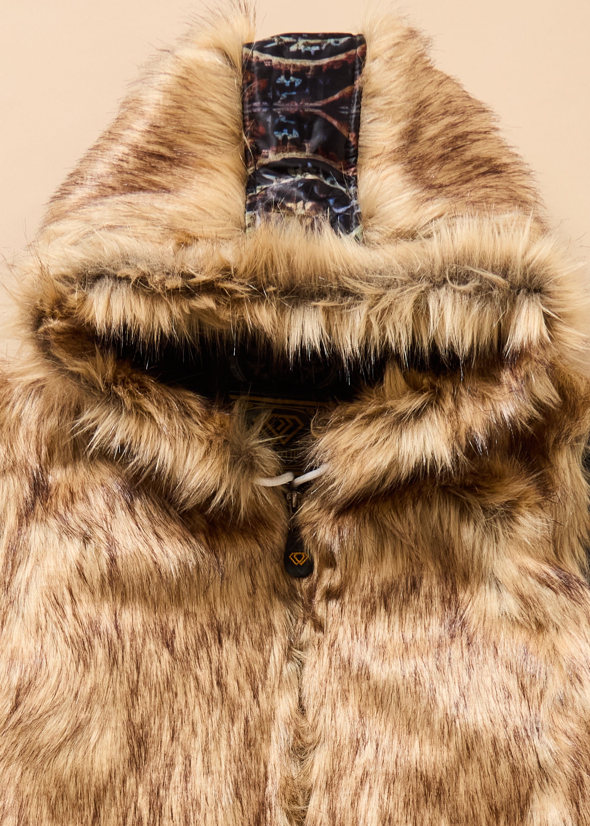 Close-up of a fur-lined hood with a brand label on a beige background