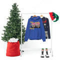 Blue graphic hoodie with festive design on rack, Christmas tree, sweater, and holiday accessories