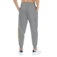 Back view of grey joggers with yellow script text, urban streetwear fashion