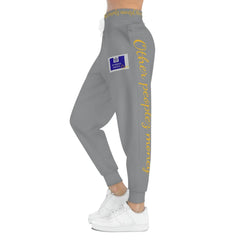 Gray joggers with yellow 'Other peoplez money' text and blue patch detail, streetwear fashion