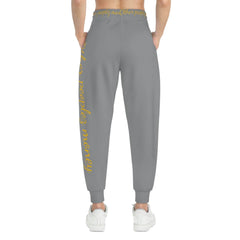 Gray streetwear joggers with gold script text along the waistband and side leg, back view
