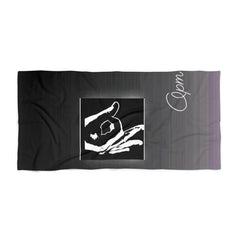 Black beach towel with bold white hand sign graphic and cursive 'Opm' lettering