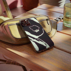 Urban graphic phone case with bold black and white design on a wooden table next to a beige bag