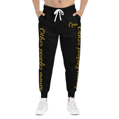 Black joggers with gold script 'Other peoples money' text, drawstring waist, streetwear style