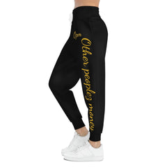 Black joggers with gold 'Other peoples money' text on side, worn with white sneakers