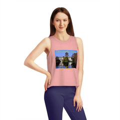 Woman wearing a pink cropped tank top with a scenic graphic and blue leggings on white background