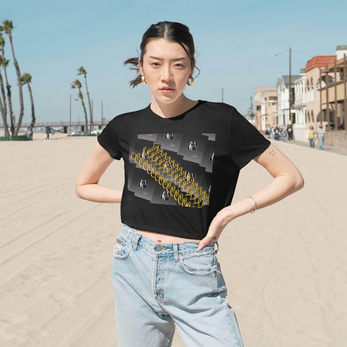 Woman wearing a black graphic cropped tee and jeans on a sunny beach street, urban streetwear style