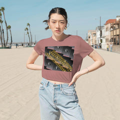 Woman wearing mauve flowy cropped tee with bold graphic text design, standing on beach